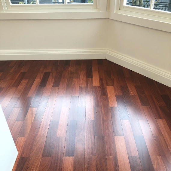 A newly funish wood floor with white walls and a window view